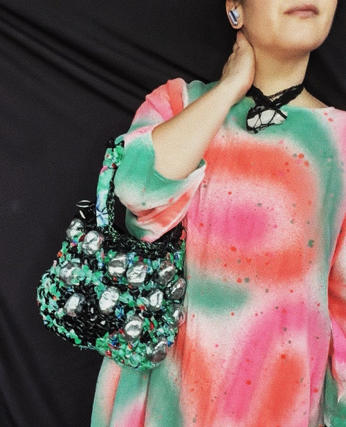 Handmade black latex and recycled fabric baguette bag worn on the shoulder showing size and strap drop