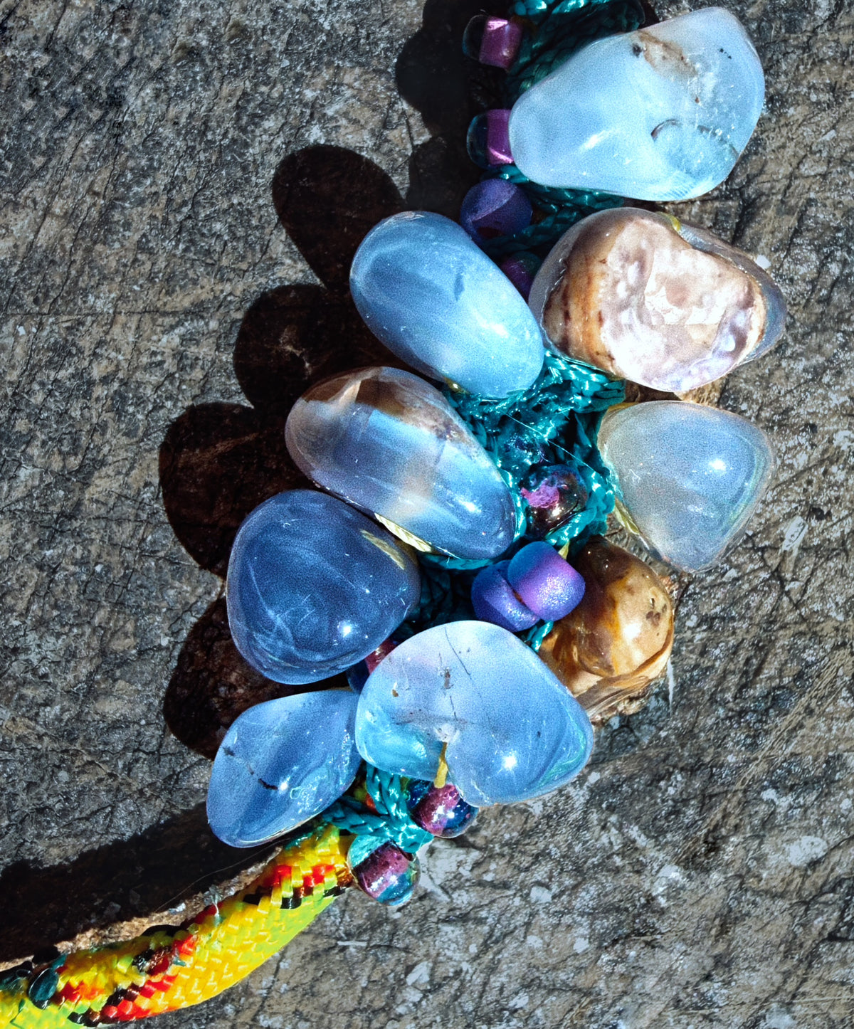 Close-up of polished bubbly chalcedony stones with tiny glass beads and melted teal nanocord